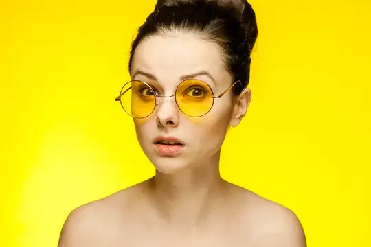 Привлекательная женщина с обнажёнными плечами в жёлтых очках, мода