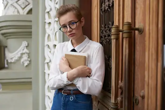 Девушка в очках с книгой у старинной двери