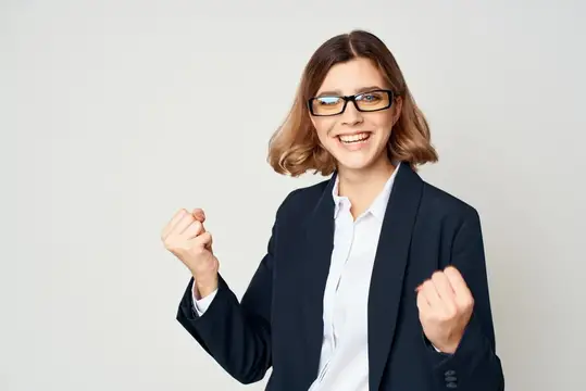 Улыбающаяся женщина в очках и деловом костюме радуется успеху