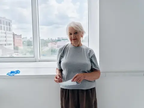 Пожилая женщина в медицинской маске проходит лечение в больнице