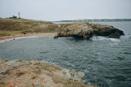 Скалистый берег с маяком и видом на город в пасмурный день