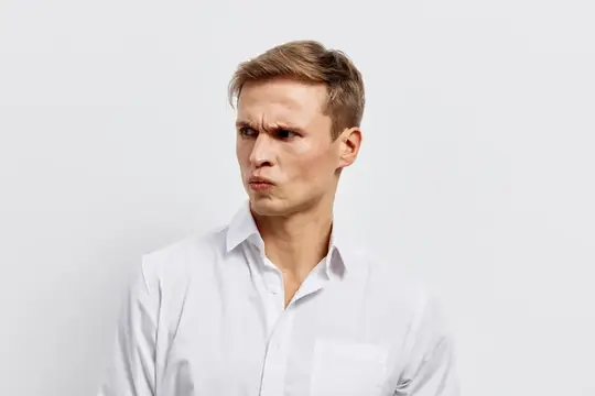 Скептически настроенный мужчина в белой рубашке смотрит в сторону с серьезным выражением лица на однотонном белом фоне
