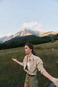 Молодая женщина раскинула руки на фоне горного пейзажа