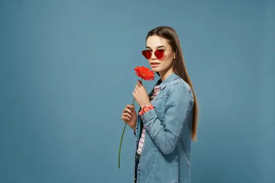 На фотографии изображена симпатичная брюнетка в солнцезащитных очках с красным цветком в качестве украшения