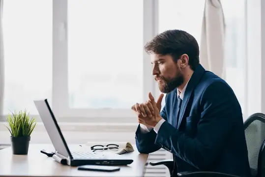 Мужчина в деловом костюме работает перед ноутбуком, демонстрируя профессионализм в сфере технологий