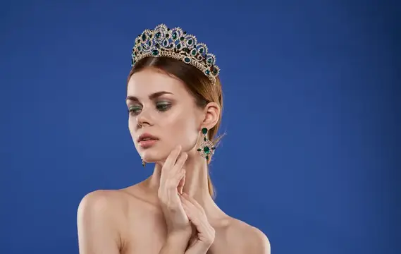 Очаровательная принцесса с диадемой на голове, в серьгах, макияж, модель на голубом фоне