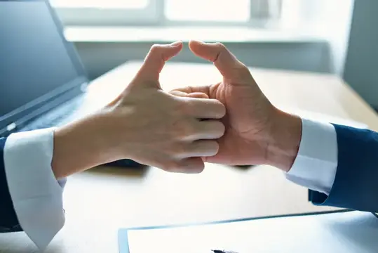 Мужские руки в деловых костюмах сложены в замок над столом