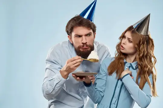 Мужчина и женщина в праздничных колпаках с тортом