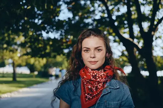 Молодая женщина с красным платком на шее в летнем парке