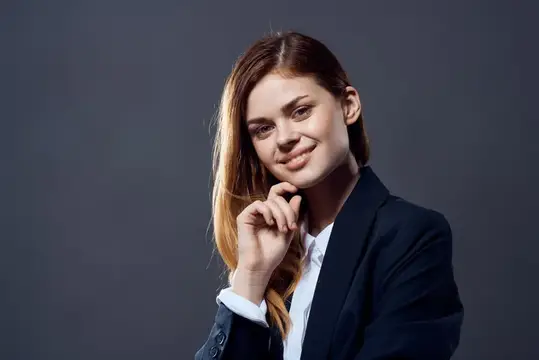 Женщина в деловом костюме, излучающая уверенность в себе, на официальном темном фоне