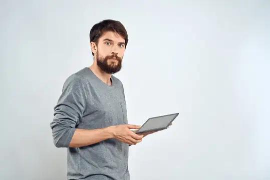 Мужчина с планшетом в руке, интернет-технологии, общение, серая куртка, светлый фон