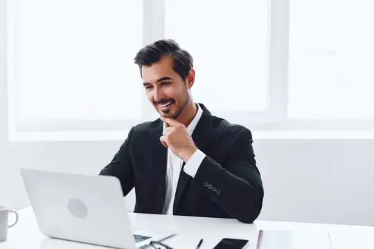 Мужчина-бизнесмен сидит за столом в офисе и работает за ноутбуком