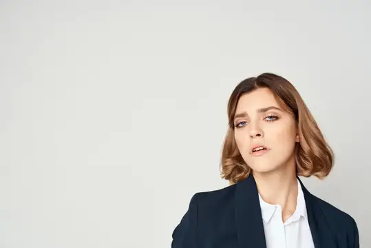 Молодая женщина в деловом костюме смотрит в сторону на светлом фоне