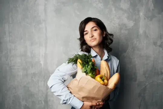 Женщина в синей рубашке с пакетом продуктов в супермаркете