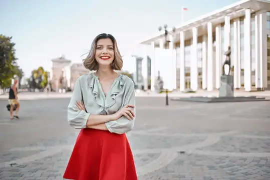 Весёлая блондинка в красной юбке идёт по улице
