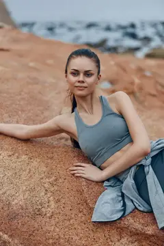 Спортивная девушка лежит на красной скале над морем