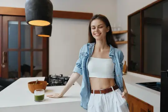 Улыбающаяся девушка в джинсовой рубашке на светлой кухне