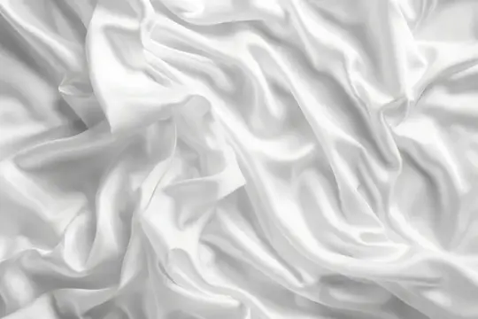 Элегантная белая атласная ткань, драпированная на поверхности, для использования в качестве фона или текстуры в фотографии или дизайне