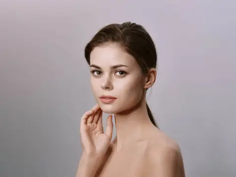 Молодая темноволосая женщина с естественным макияжем на сером фоне