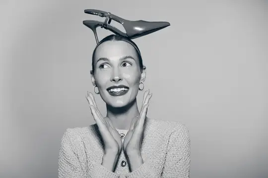 Улыбающаяся женщина с туфлей на голове в студии