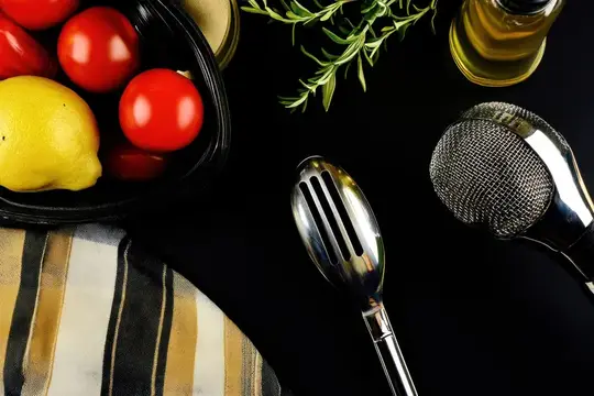 Помидоры, лимон и столовые приборы на чёрном фоне
