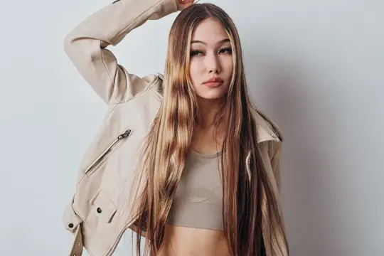 Азиатская девушка с длинными светлыми волосами в бежевой куртке