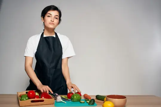 Женщина в черном фартуке на кухне, овощи, свежая еда, витамины