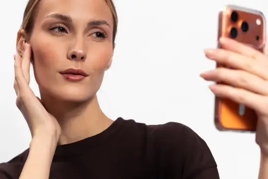 Молодая женщина делает селфи на смартфон на белом фоне