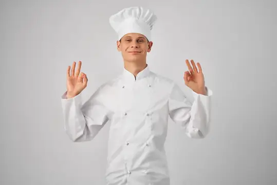 Веселый шеф-повар-мужчина жестикулирует руками на кухне ресторана