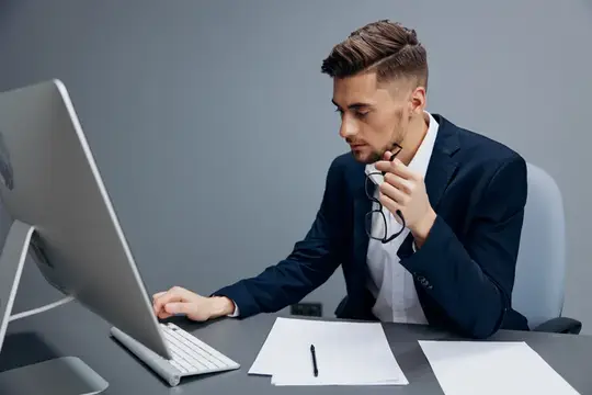 Сосредоточенный мужчина в костюме работает за компьютером в офисе