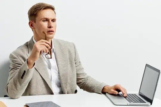 Задумчивый мужчина в пиджаке с очками у ноутбука