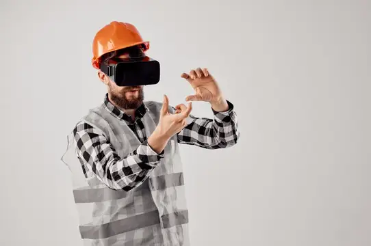 Строитель в каске и VR-очках жестикулирует на сером фоне