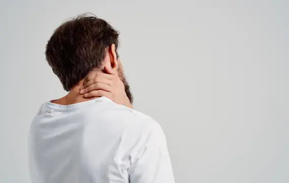 Мужчина с темными волосами держится за шею со спины