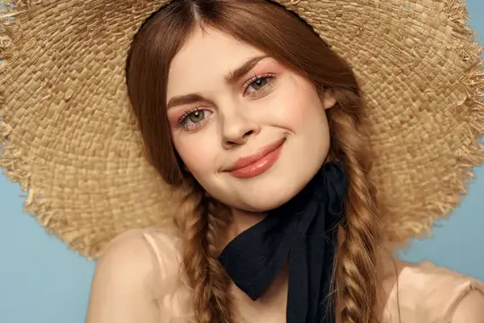 Молодая девушка в соломенной шляпе с косичками на голубом фоне