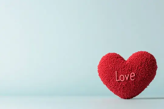 Яркий красный объект в форме сердца с надписью «Love» на мягком пастельно-голубом фоне