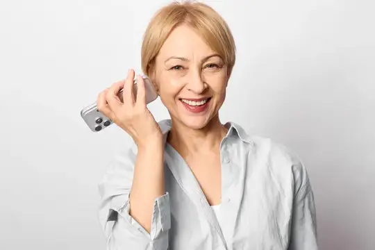 Улыбающаяся блондинка держит смартфон у уха на светлом фоне