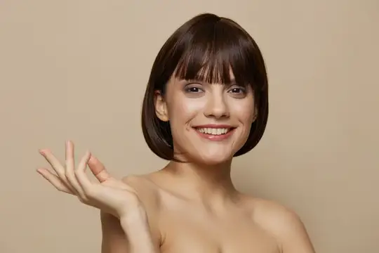 Улыбающаяся шатенка с короткой стрижкой жестом приглашает зрителя