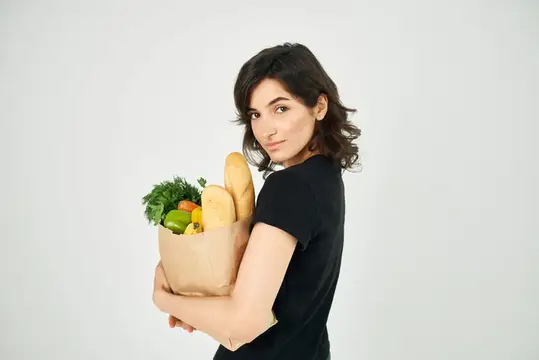 Брюнетка с бумажным пакетом продуктов смотрит через плечо