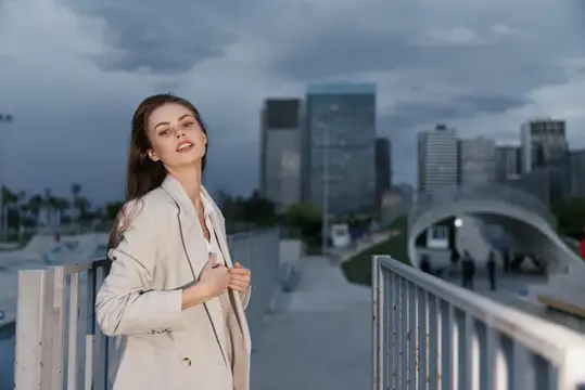 Молодая женщина в светлом пиджаке на фоне вечернего города