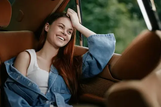 Рыжеволосая девушка смеётся в салоне автомобиля
