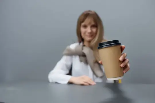 Улыбающаяся женщина держит бумажный стакан кофе на сером фоне