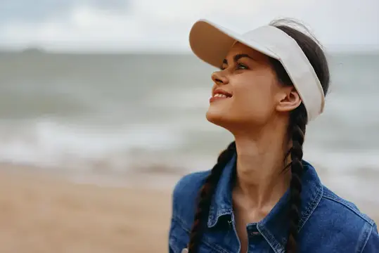 Улыбающаяся молодая привлекательная женщина наслаждается расслабляющим пляжным отдыхом