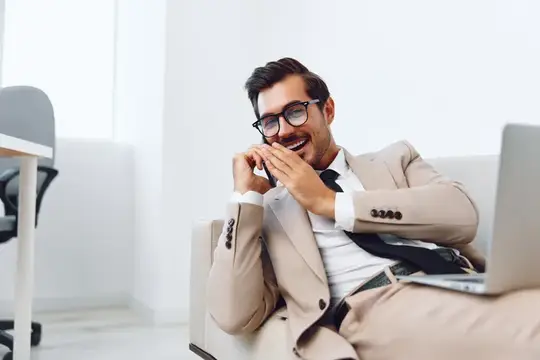 Мужчина разговаривает по смартфону, используя ноутбук