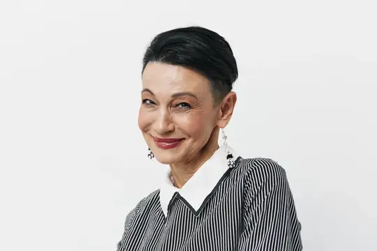 Улыбающаяся пожилая женщина с тёмными волосами на белом фоне