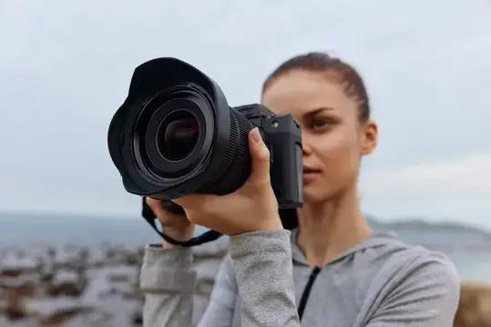 Молодая женщина фотографирует на камеру у моря