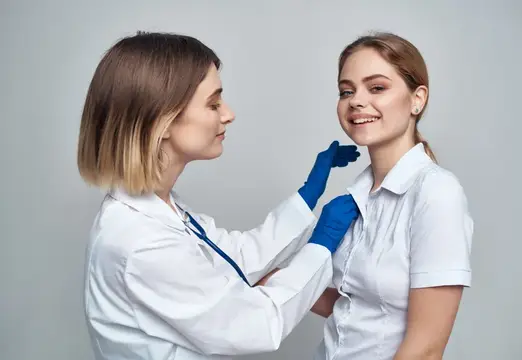 Врач в синих перчатках осматривает улыбающуюся пациентку