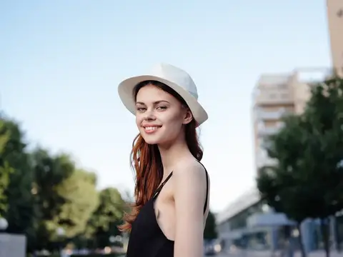 Улыбающаяся девушка в белой шляпе на летней городской улице