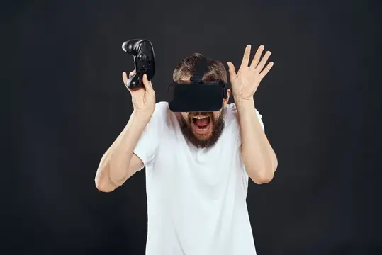 Бородатый мужчина в VR-очках кричит от восторга с контроллером в руке