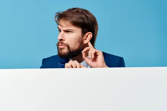 Задумчивый бородатый мужчина в синем пиджаке на голубом фоне
