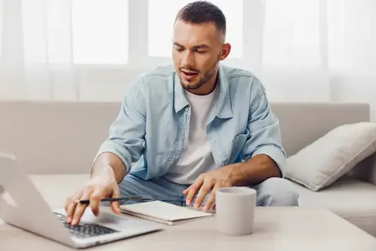 Сосредоточенный мужчина занимается удаленной работой в своем уютном домашнем рабочем пространстве